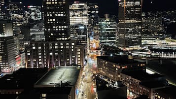 A nighttime cityscape with illuminated buildings and a prominent tower with a colorful spire.