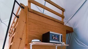 Una cuina de fusta compacta amb fogó integrat, un rentatalleres i una estant amb cafetera.
