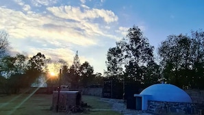 A rustic outdoor setting with a stone wall, a small archway, and a blue-roofed structure.