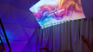 A tent with a colorful projection on the ceiling, a bed, and a small table.
