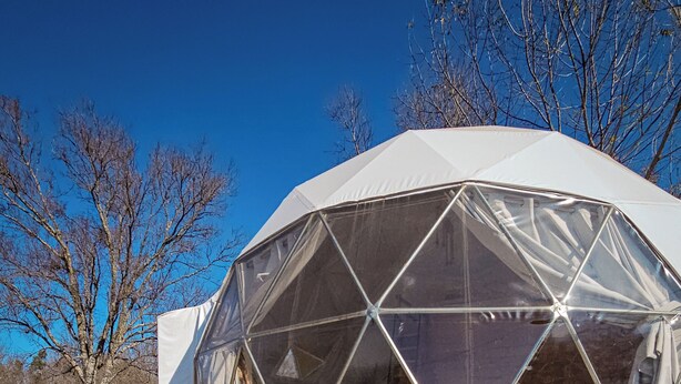 Une structure en forme de dôme géodésique dotée d’une piscine et d’un espace extérieur aménagé pour s’asseoir.