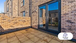 A modern brick building with a large glass sliding door, a paved patio, and a visible logo for 'Prestige Living'. - Central Home | Fast Wi-Fi | Smart TVs | Sleeps 5 (Birmingham)