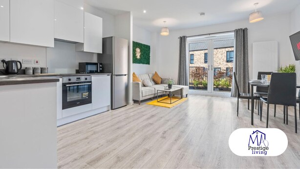 A modern apartment with a kitchen, dining area, and living room. It features a large window, a flat-screen TV, and a green wall decoration. - Central Home | Fast Wi-Fi | Smart TVs | Sleeps 5 (Birmingham)
