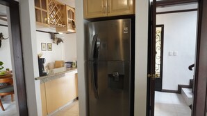 Eine Küche mit einem Edelstahlkühlschrank, Holzschränken und einer Arbeitsplatte mit diversen Gegenständen.