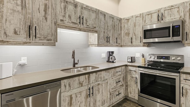 A modern kitchen with wooden cabinets, stainless steel appliances, and a white tiled backsplash. - 124 Hurontario Unit 3 (Collingwood)