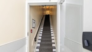 A hotel hallway with a carpeted staircase, a fire alarm, and a door on the right. - 124 Hurontario Unit 3 (Collingwood)