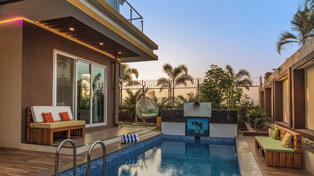 Ein Schwimmbad mit Holzterrasse, Sitzbereichen und einer Glastür zu einer überdachten Terrasse.