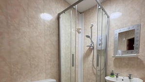 A bathroom with a glass-enclosed shower, a toilet, a sink, and a mirror. - No 34 Vance Road (Blackpool)