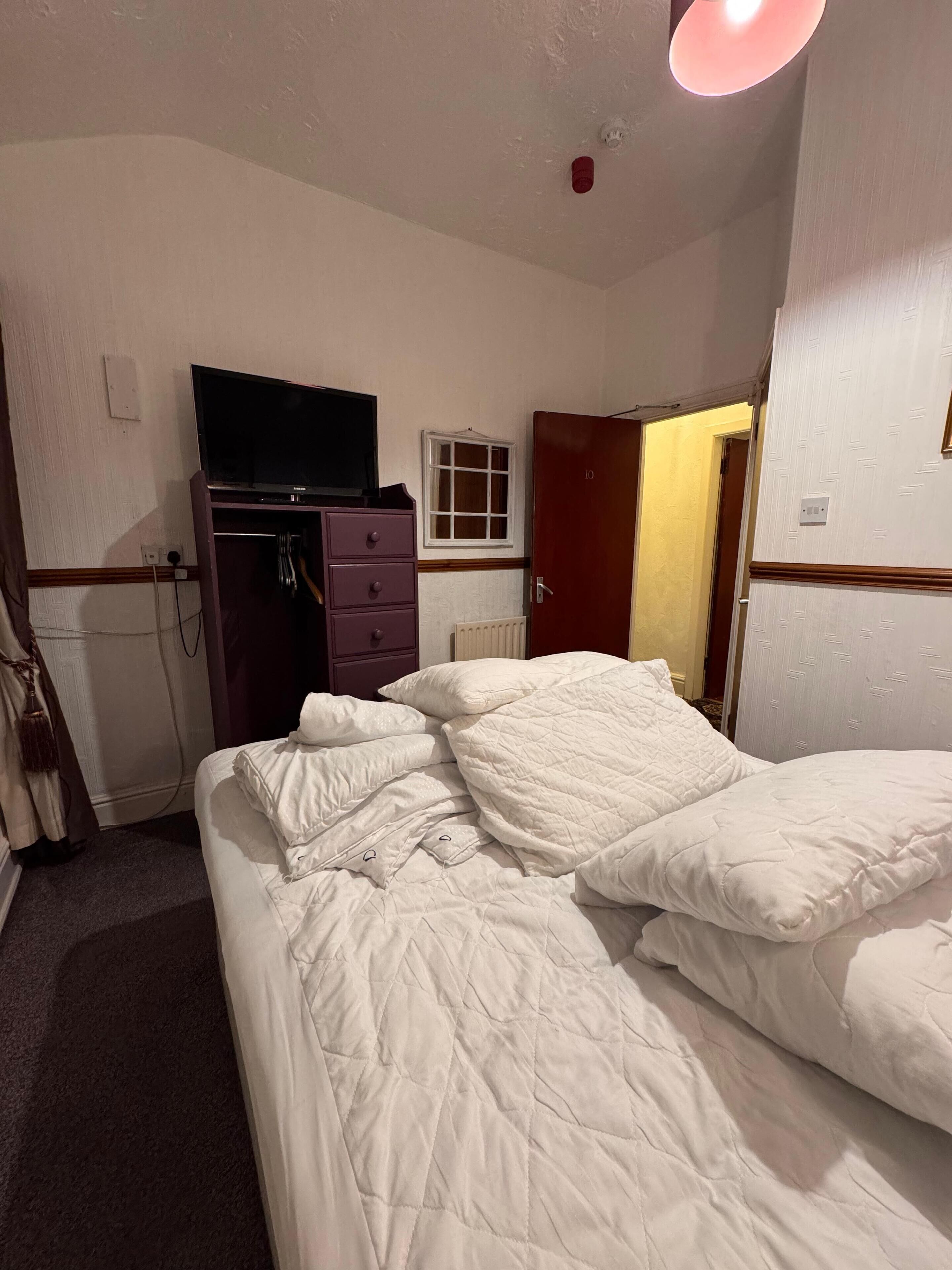 Una habitación de hotel con una cama, un aparador, un televisor y una ventana.