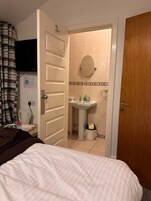 Een hotelkamer met een bed, een badkamer met wastafel en spiegel, en een aan de muur bevestigde televisie.