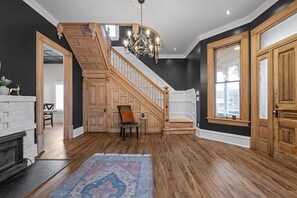A spacious room with a wooden staircase, a chandelier, and a large window. - Historic Muzzy Mansion near downtown Spokane. Great for business & personal use. (Spokane)