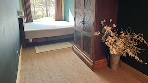 Une chambre à coucher avec un lit, une fenêtre, un ventilateur de plafond, une armoire et un arrangement floral.