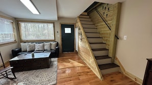 Un salon avec un escalier en bois, un canapé et une table basse.