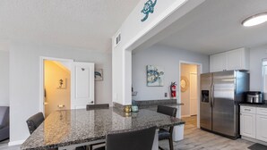 Una cocina con encimeras de granito, electrodomésticos de acero inoxidable y una zona de comedor con sillas y una mesa.