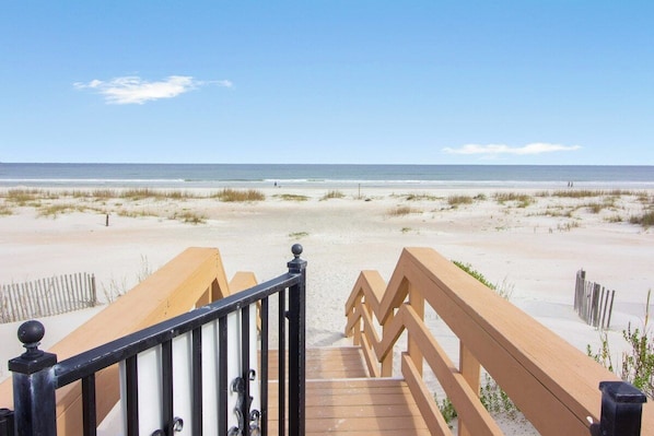 A wooden boardwalk leading to a sandy beach with a clear sky. - Paws Welcome at Ponce Landing 25 (St. Augustine)