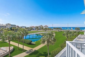 Ein Poolbereich mit einer Brücke, Palmen und Blick aufs Meer.