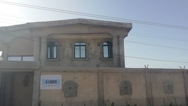 A building with a sign reading "À LOUER" and a contact number. - Peaceful 6-bedroom house with AC in vibrant Lome (Lome)