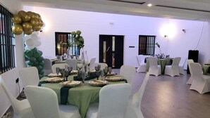 A banquet hall with round tables set for dining, white chairs, and a decorative balloon arch. - Peaceful 6-bedroom house with AC in vibrant Lome (Lome)