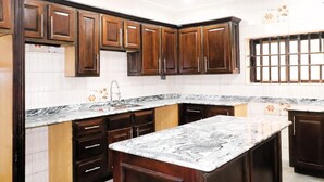 A kitchen with dark wooden cabinets, white subway tiles, and a marble countertop.