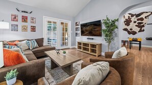A modern living room with a sectional sofa, a wooden coffee table, and a TV mounted on the wall.