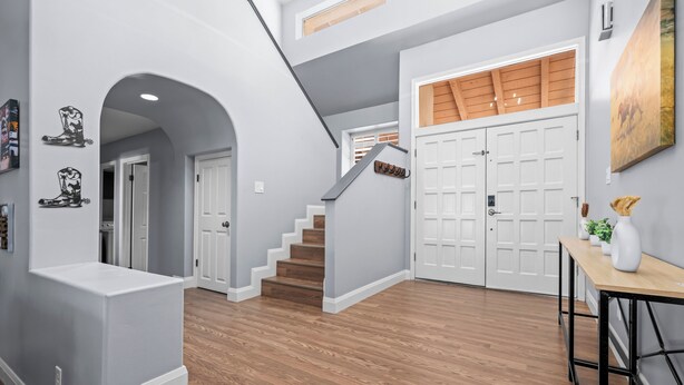 A modern interior with a staircase, wooden flooring, and white walls.