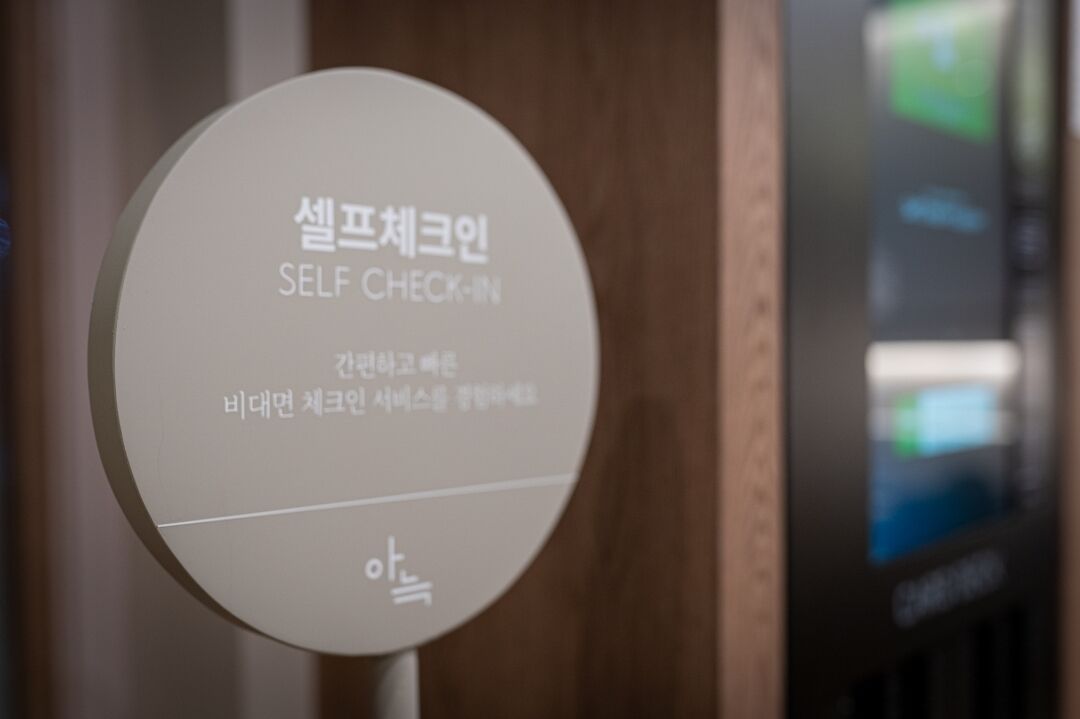 A circular sign with text in Korean and English, indicating a self-check-in service.