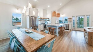 Una cocina amplia con una mesa de comedor de madera, sillas azules y una isla central con taburetes.