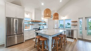 Una cocina moderna con una isla grande, electrodomésticos de acero inoxidable y taburetes de mimbre.