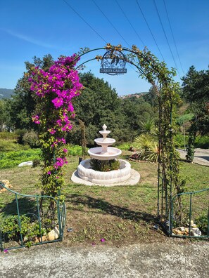 A garden with a fountain, a sign reading 'Cuquit's Garden,' and a metal archway.