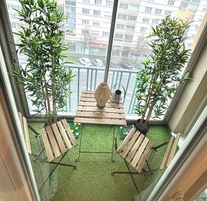 A balcony with two wooden chairs, a small table, and two potted plants. - 2-Bedroom Apartment in the Heart of Macon - Secure Parking + Bike Storage (Mâcon)