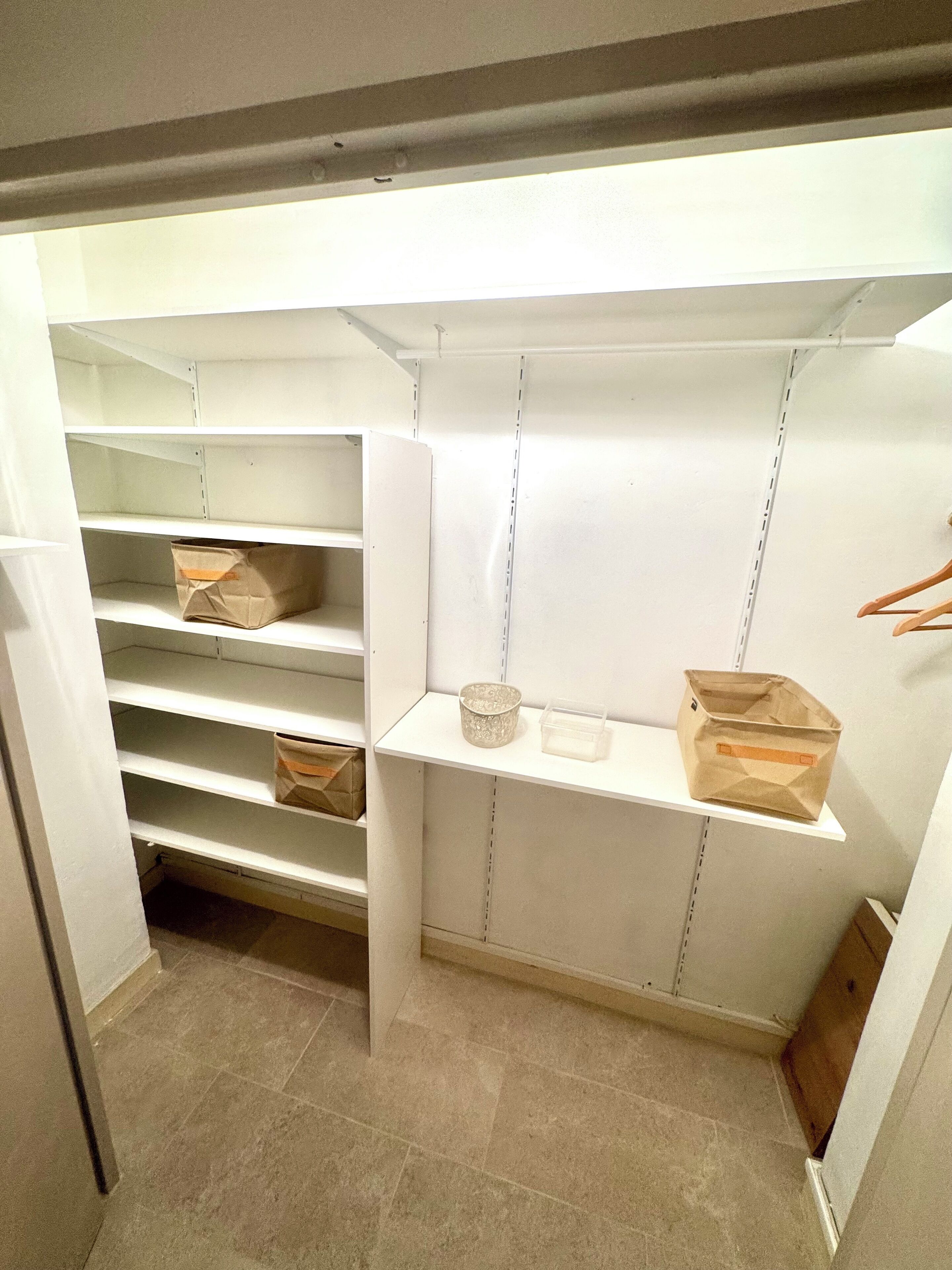 A storage closet with multiple shelves and hanging space.
