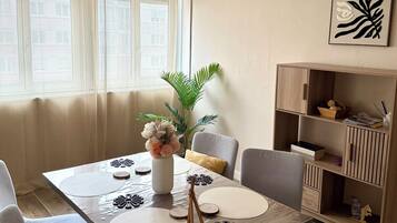 Een eetgedeelte met een houten tafel, stoelen, een vaas met bloemen en een hanglamp.