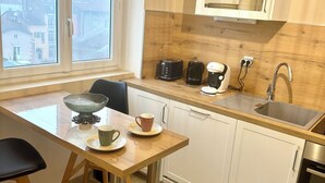 Eine moderne Küche mit Holzarbeitsplatte, Spüle, Kaffeemaschine und einem Fenster mit Blick auf Gebäude.