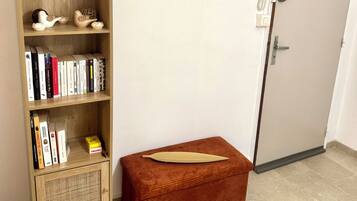 Una habitación con una estantería de madera, un pequeño cofre de madera y una puerta.