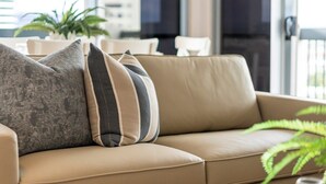 A beige leather sofa with three pillows in a modern interior setting. - 12th Floor Riverfront Retreat Views Walk to Beach (Surfers Paradise)
