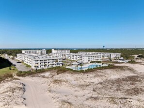 Ein Strandhotel mit mehreren Gebäuden, einem Schwimmbad und einem Sandstrand.