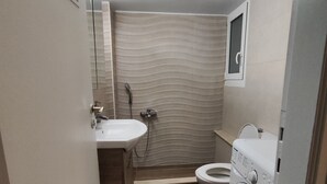 Een kleine badkamer met een wastafel, toilet en wasmachine.