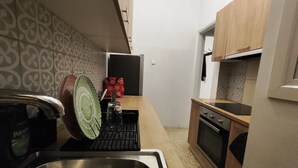Een kleine keuken met een roestvrijstalen spoelbak, een magnetron en houten keukenkastjes.