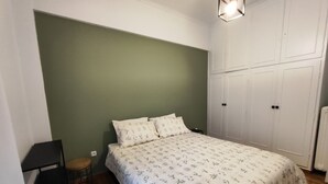 Een slaapkamer met een bed, een stoel, een kledingkast en een nachtkastje.
