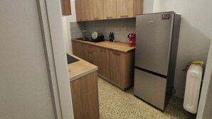 Een kleine keuken met houten kastjes, een roestvrijstalen koelkast en een granieten aanrecht.