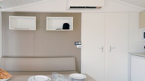 A modern, minimalist room with a dining table set for four, a bench, and two white cabinets. - Waterfront mobile home (Saint-Florent)