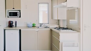 A compact kitchen with a microwave, coffee maker, and a small refrigerator. - Waterfront mobile home (Saint-Florent)