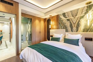 Ein modernes Hotelzimmer mit einem großen Bett, Holzwandverkleidung, Marmorwand und einer Duschkabine aus Glas.