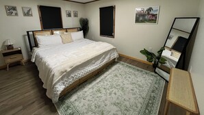 A bedroom with a bed, a nightstand, a mirror, a window, and a wall-mounted picture. - Welcome to the Butterscotch Bungalow! (Hummelstown)