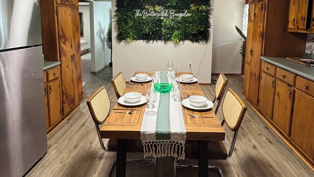 A dining area with a wooden table set for six, surrounded by wooden cabinets and a green wall decoration. - Welcome to the Butterscotch Bungalow! (Hummelstown)