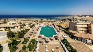Un complexe hôtelier doté d’une piscine centrale, de plusieurs espaces de détente et offrant une vue sur la plage et l’océan.