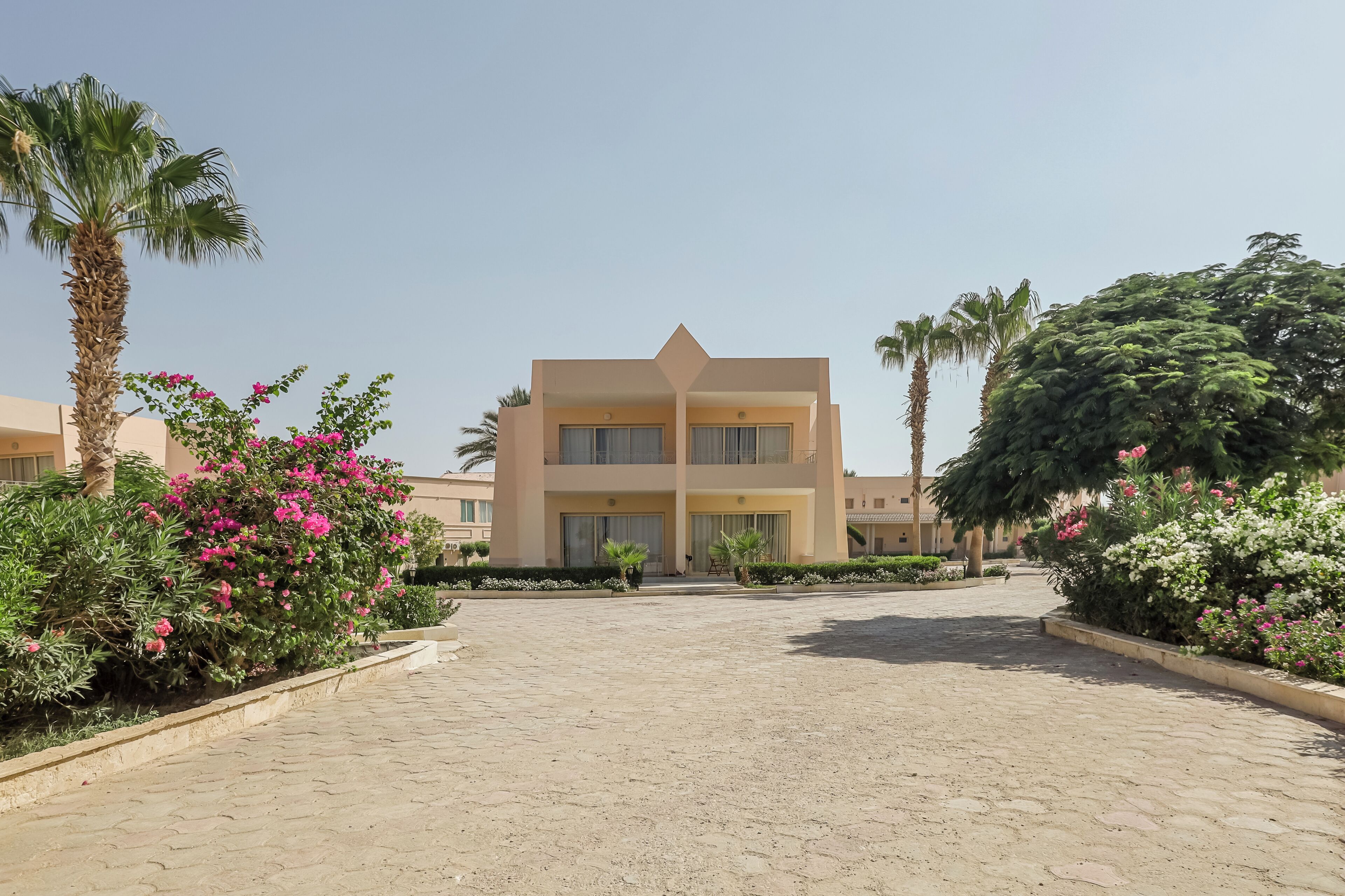 Un hôtel à plusieurs étages doté d’une cour intérieure, entourée d’une végétation luxuriante et de palmiers.