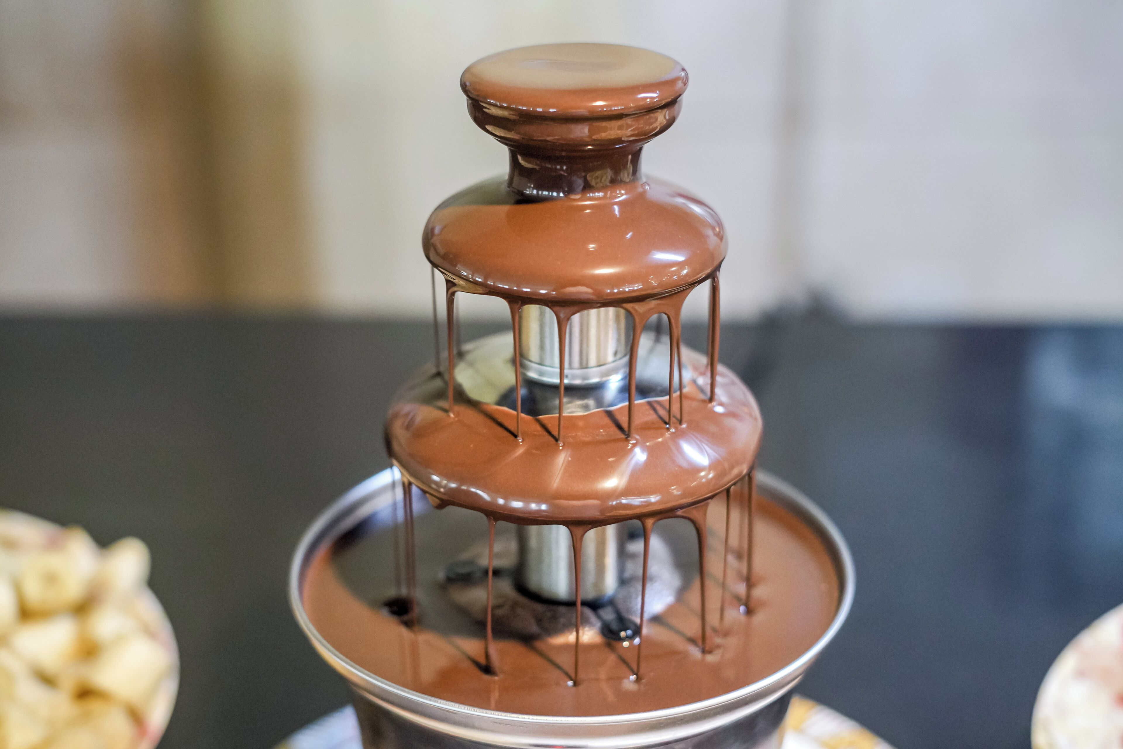 A chocolate fountain with a metallic base and a glass container.
