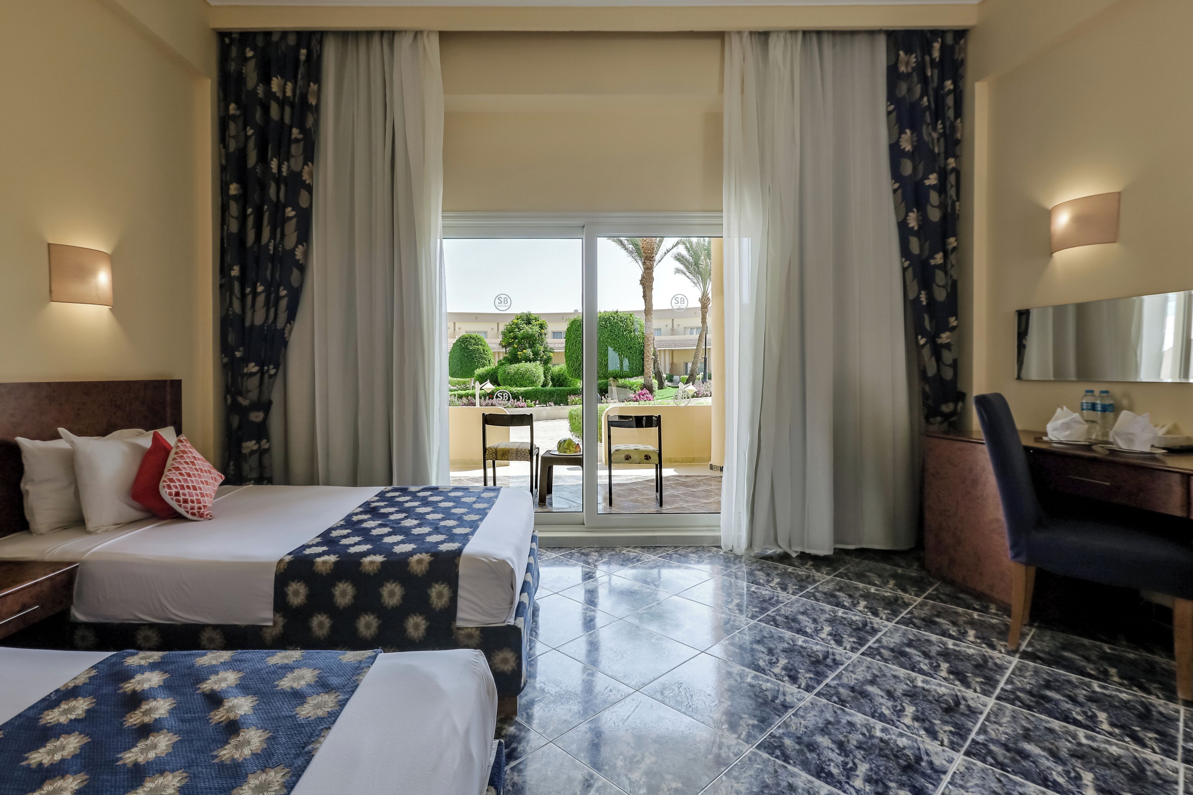 A hotel room with a bed, a desk, a chair, and a view of the outdoor area.