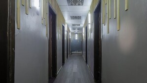 Un pasillo largo y estrecho con puertas a ambos lados, techo con diseño y suelo de madera.